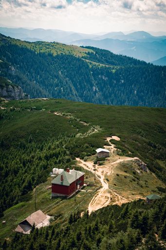 A vertical shot of a house on the top of a green mountain