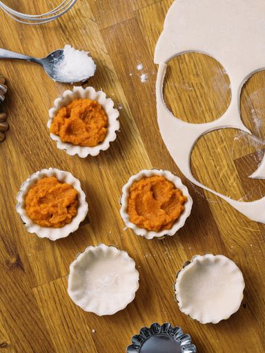 A vertical shot of homemade small pie crusts during a baking process on a wooden table