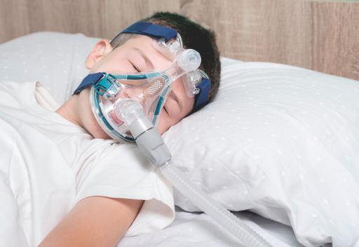 A child wearing a nebulizer mask sleeping on his hospital bed