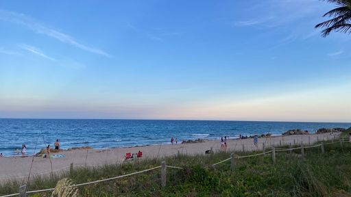 A beautiful beach with people resting at a soft sunset