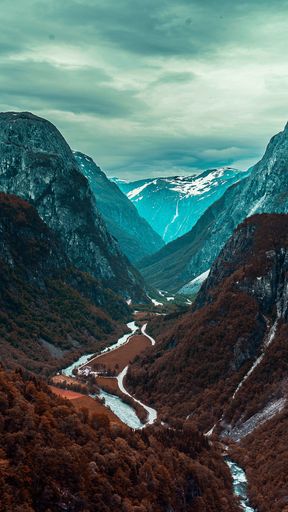 A vertical shot of high snowy mountains in the midst of serene landscape