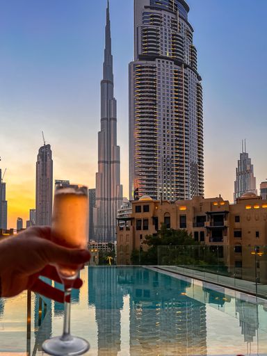 View of Dubai skyline at sunset with champagne in hand