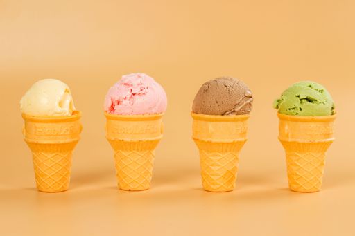 A closeup of different flavored ice cream cones on a beige background