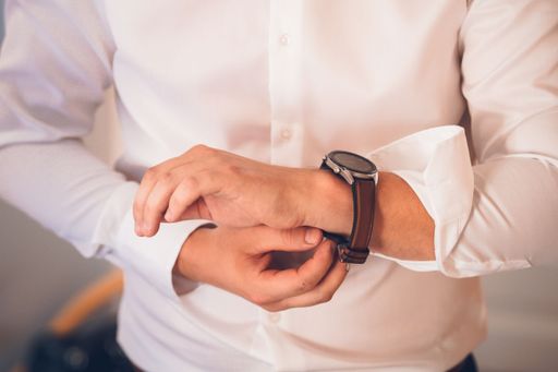 A closeup shot of a businessman checking the time on a wristwatch. The groom puts a watch on his wrist