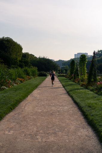 A vertical shot of a young woman jogging in a park in the morning in the Garden of Plants in Paris