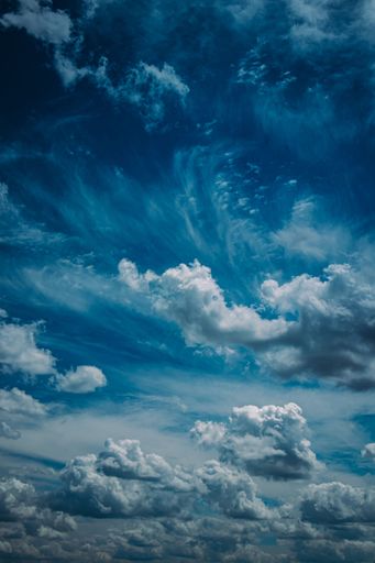 A vertical shot of clouds in the sky. Dramatic direction of clouds in bright blue sky