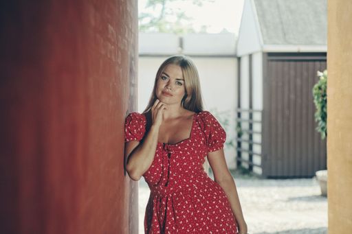 A young beautiful blonde female in a spotted red white dress posing
