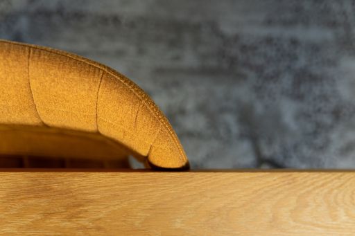 Downward shot of the edge of a desk top and chair in the morning