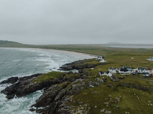 Beautiful buildings near the rocky shoreline of the wavy sea on the Isle of Tiree, Scotland