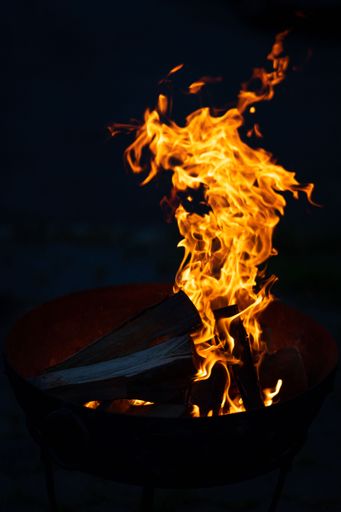 A vertical shot of flaming logs on a bonfire during nighttime
