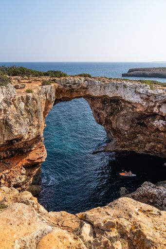 A vertical shot of a stone arch over water in Mallorca, Spain