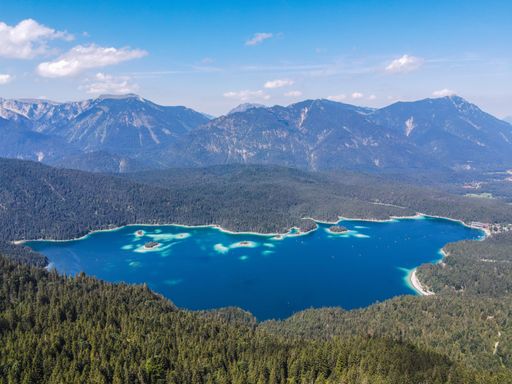 An aerial view of Elbsee lake surrounded by dense trees and mountains