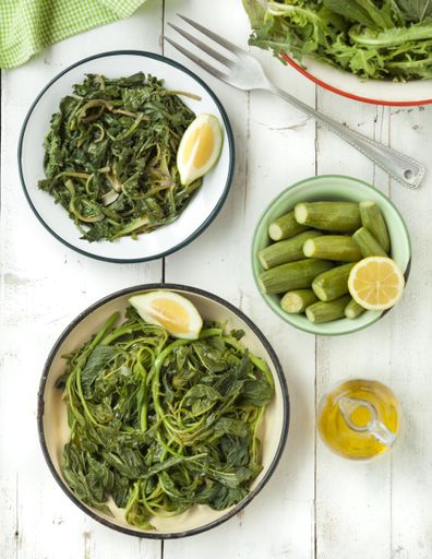 A high angle shot of namul and cucumbers with lime in metal bowls on a wooden table
