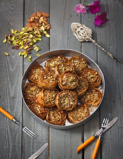 A vertical high angle shot of rolls made with pumpkin seeds and almonds in a metal pot on a wooden surface