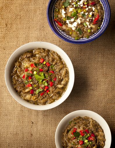 A vertical high angle shot of three bowls of vegetable soup on a brown surface