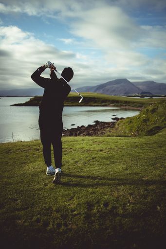 A vertical shot of a man golfing on the coast of Hofn, Iceland