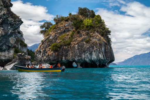 A group of tourists on a boat in General Carrera Lake by Marble Cathedral cliff