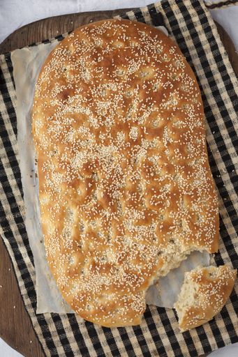 A vertical high angle shot of cut bread with sesame on a striped cloth