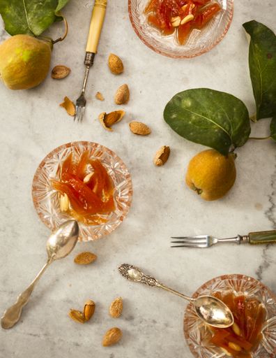 A high angle shot of glass bowls with quince jam and almonds on a white surface