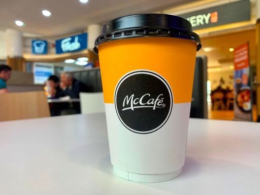 A selective focus shot of a McCafe hot drink takeaway cup on a white table
