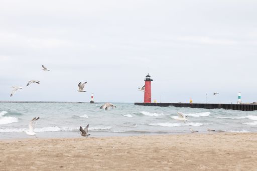 A red lighthouse from a sandy beach on a sunny day