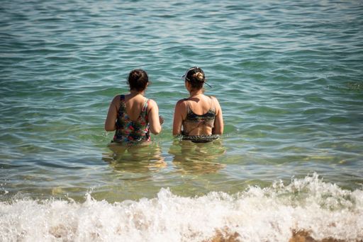 Mother and daughter in bikini entering the water at Porto da Barra beach in Salvador, Bahia