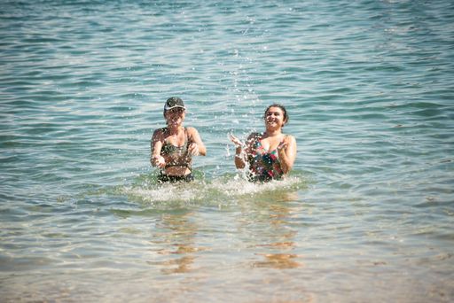 Two women splashing water on the beach at Porto da Barra in Salvador, Bahia