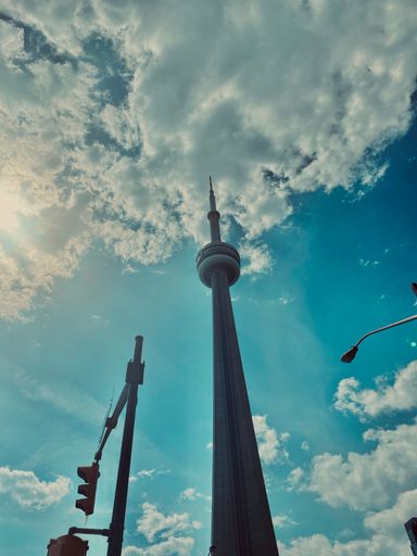 A vertical low angle shot of the beautiful CN tower against a blue cloudy sky in Toronto, Canada