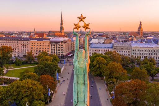 The Freedom Monument surrounded by buildings and trees under the sunlight in Riga, Latvia