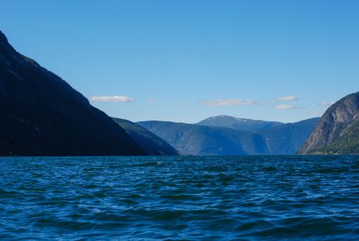 A beautiful view of a calm blue sea with mountains under the clear sky