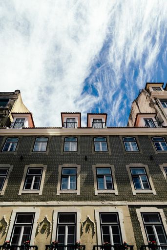 A low angle shot of the facade of a classic building with many windows against a cloudy sky