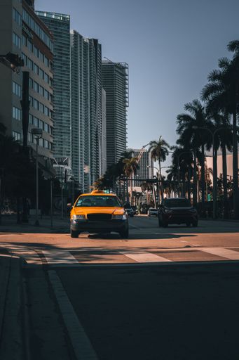 A vertical shot of a yellow taxi in the street of Miami city