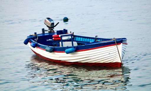 A small wooden fishing boat with a motor on the water