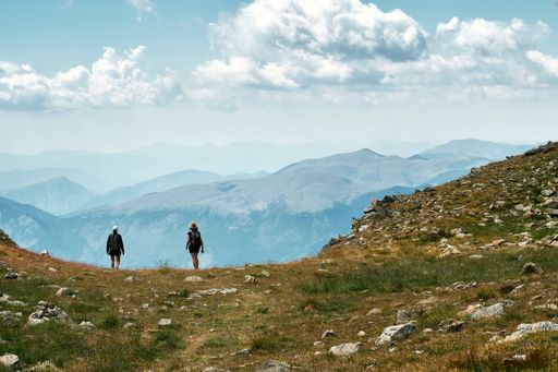 A back view photo of hikers standing at the edge of a hill in the French Riviera backcountry with a view of endless layers of a mountain range