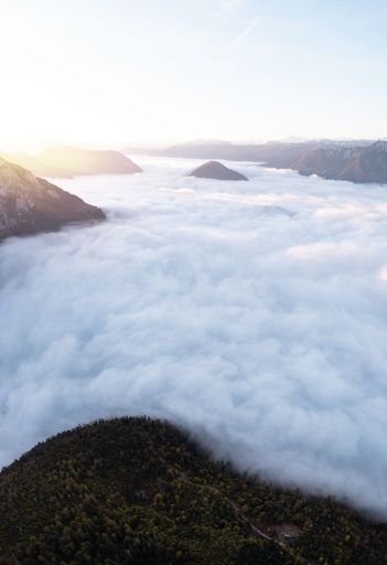 A vertical shot of clouds covering the mountains and leaving the higher peaks out