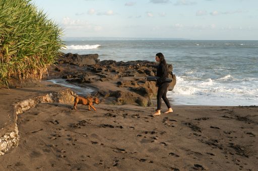 Bali lifestyle. Sporty caucasian woman with a puppy on the beach. On the way to yoga practice in Bali