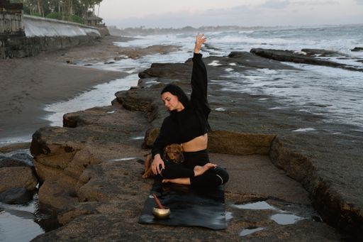 Yoga with a dog on the beach. Young woman doing relaxation and meditation session in Bali beach. Bali yoga lifestyle