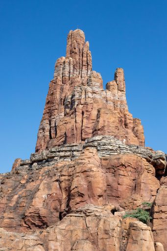 A vertical shot of high rocky cliffs under the blue clear sky