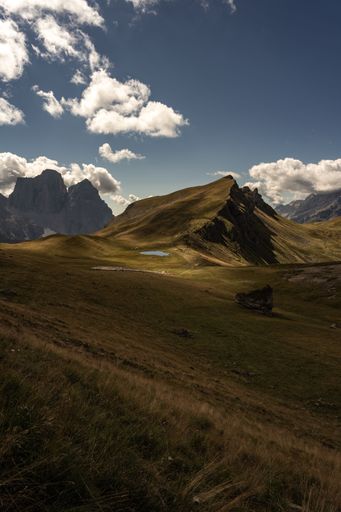 A vertical shot of scenic Dolomite Mountains in Italy covered with green meadow