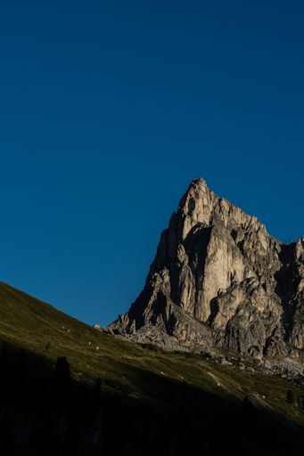 A vertical shot of scenic Dolomite Mountains in Italy covered with green meadow