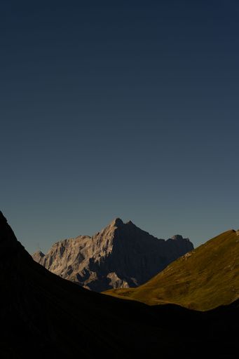 A vertical shot of scenic Dolomite Mountains in Italy covered with green meadow
