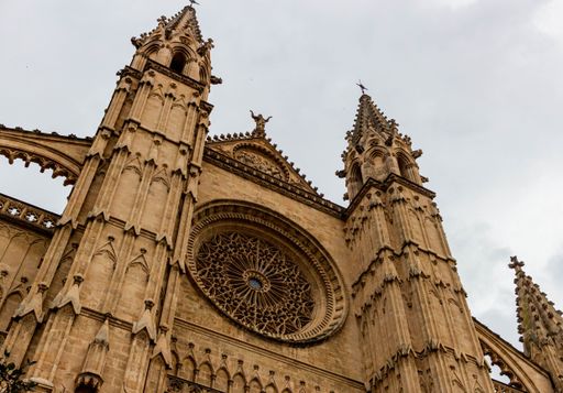 A low angle facade view of the gothic Palm Cathedral under the cloudy sky