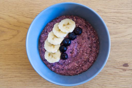 A top view of a blueberry smoothie bowl decorated with berries and sliced bananas