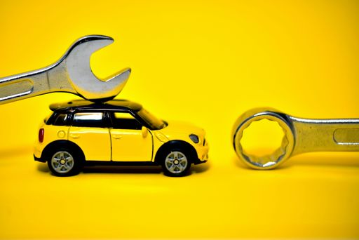 A closeup of a toy car with wrenches on a yellow background - a concept of car maintenance