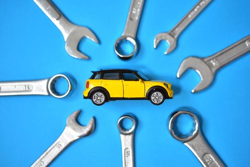A closeup of a toy car with wrenches on a blue background - a concept of car maintenance