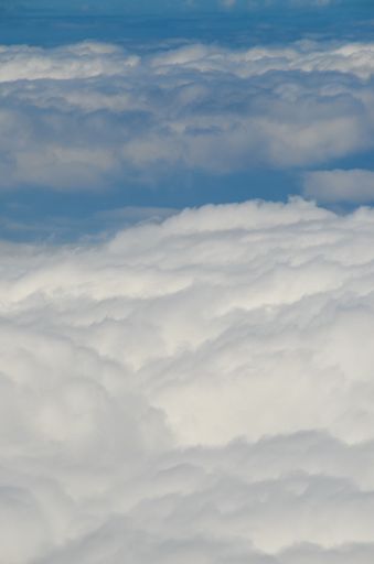 A vertical shot of high clouds piled against the bright blue sky during daytime