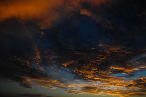 A scenic shot of dramatic dark orange clouds scattered in the sky at sunset