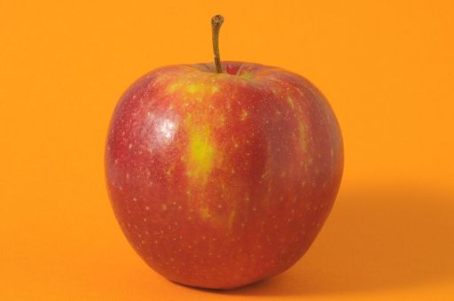 One Juicy Hot Red Apple over a Colored Background