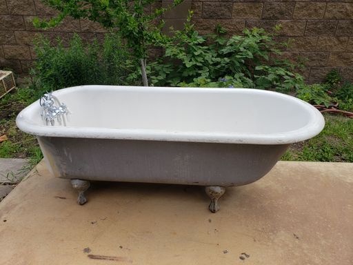 A view of an outdoor white iron bathtub.
