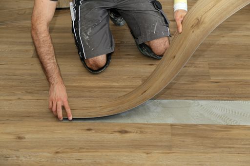 A worker installing new vinyl tile floor